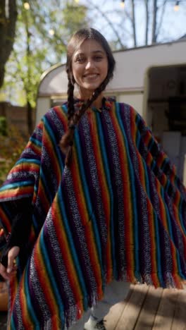 teenage girl in a colorful poncho near a camper