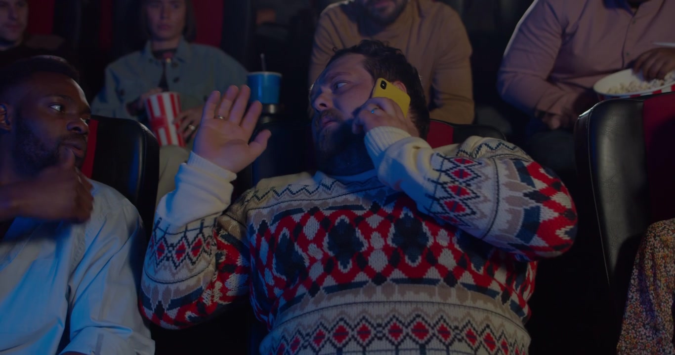 Mand taler i telefon under film i biografen
