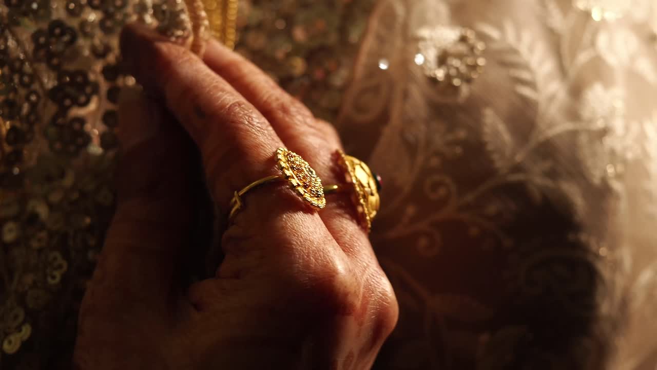 Mano di donna con anello d'oro tradizionale e vestito ricamato