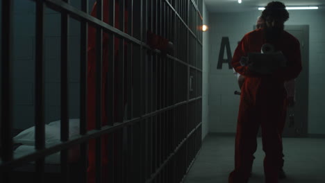 Gefängniswärter-Führt-Kriminellen-In-Orangefarbener-Uniform-In-Die-Gefängniszelle