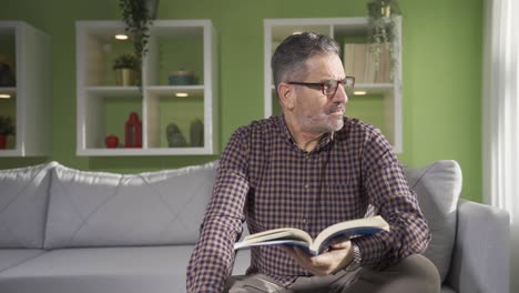 hombre maduro leyendo un libro en casa en un día soleado.