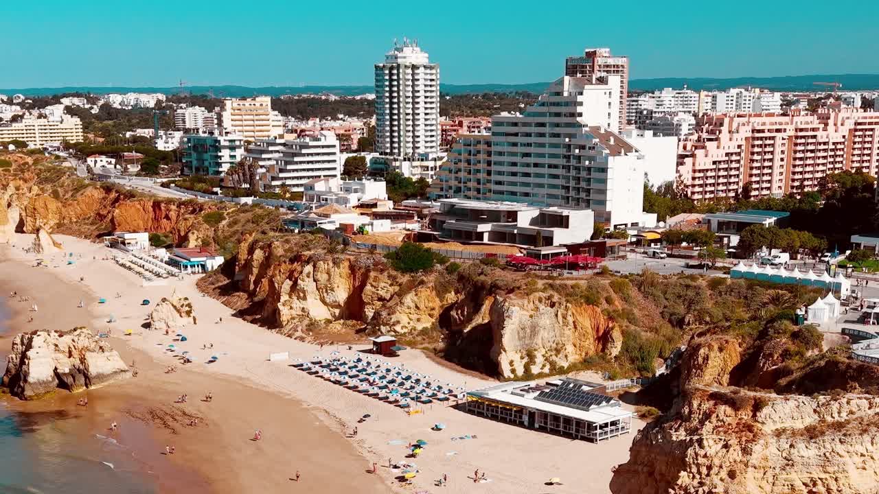 Besøgende nyder stranden og udsigten over byen i Portugal i solskinsvejr