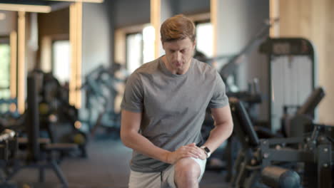 attractive fitness man warming up legs at gym. sportsman making squats at gym.