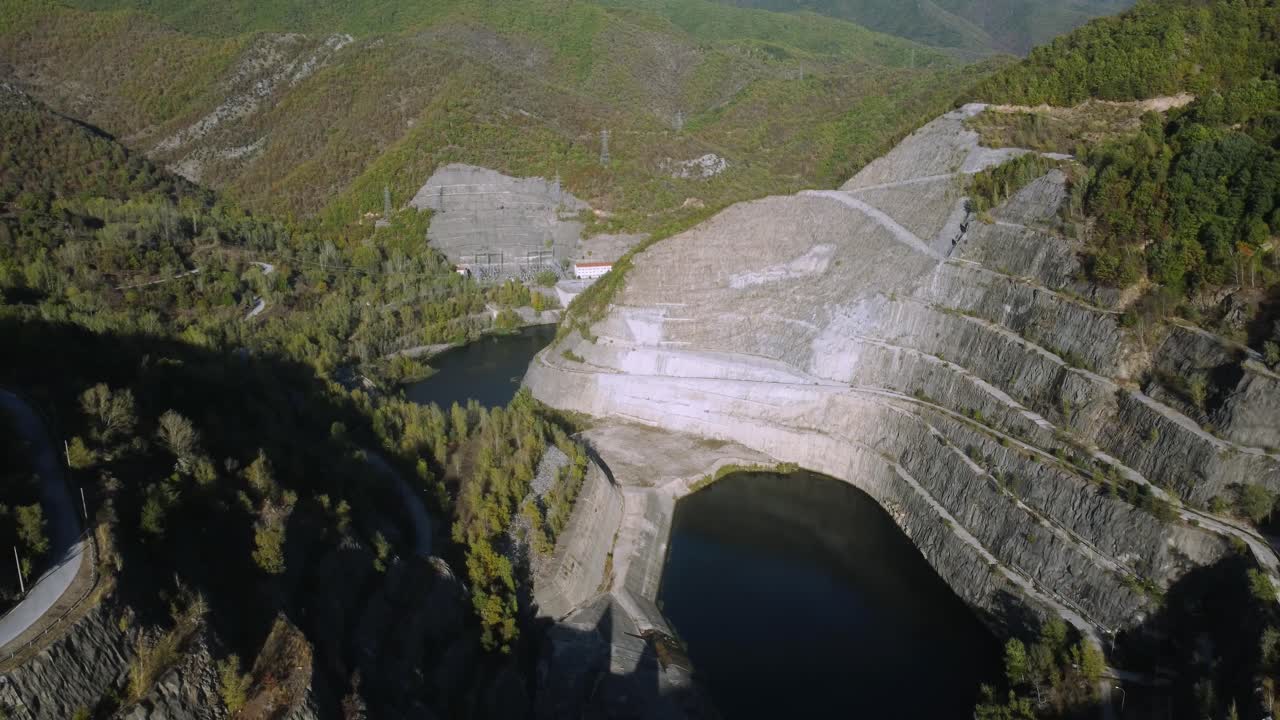 Aerial establishing of large dam in the mountains in spring