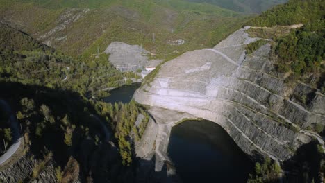 aerial establishing of large dam in the mountains in spring