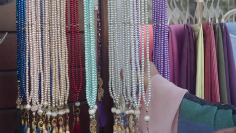 una mujer mirando una selección de cuentas de oración en un mercado