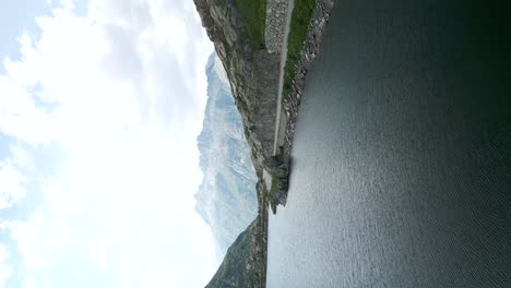 Aerial-Flying-Over-Rooftop-building-Beside-Lake-At-Grimsel-Pass