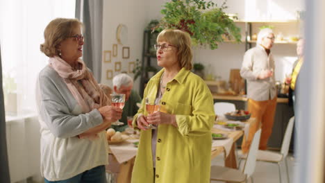 senior women chatting over wine at home party