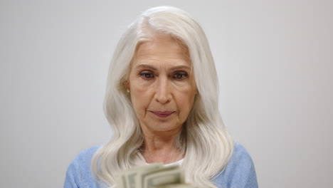 satisfied old woman counting money indoors. happy lady having banknotes inside.