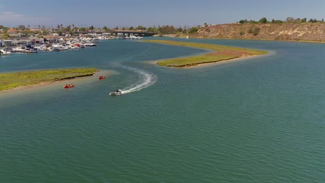 aerial view of a small boat and kayakers exploring an inlet in newport beach, california