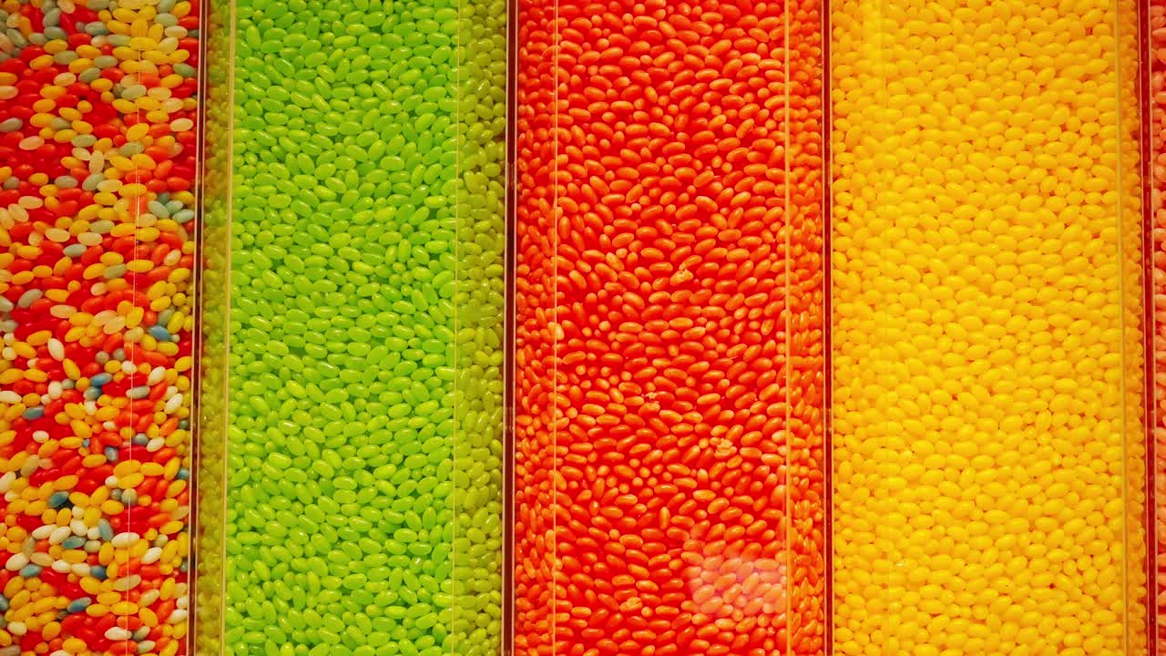 Saturated jelly beans fill clear vertical bins in bright candy shop interior