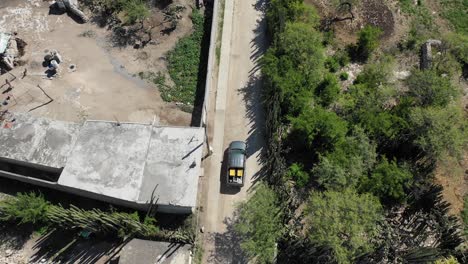 from above a pickup truck drives on dirt road through poor village in desert