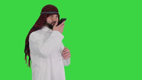 arabian businessman recording voice message or using voice digital helper on a green screen, chroma key