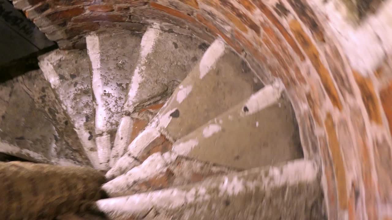 спускается по спиральной кирпичной лестнице в старой церковной башне