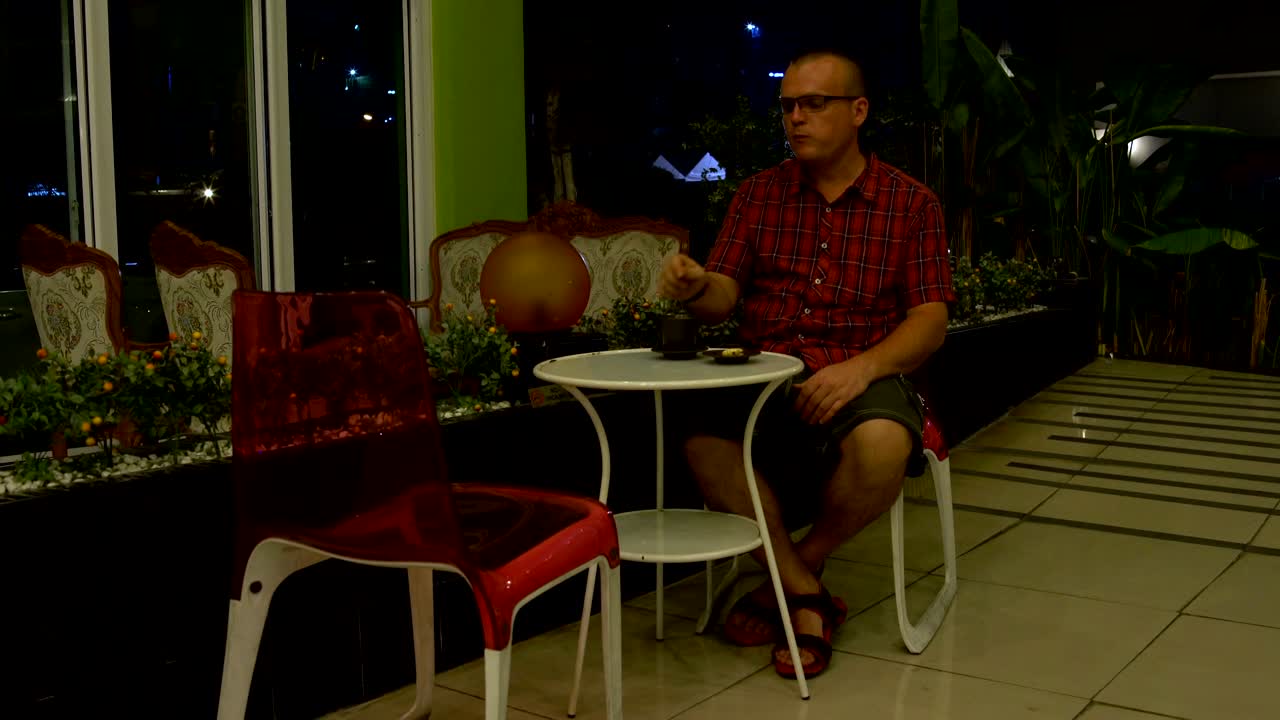 un hombre se sienta en una mesa en el vestíbulo del hotel y bebe café con galletas