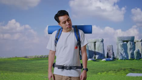 asian male hiker with mountaineering backpack shaking his head and making unsatisfied face while traveling in stonehenge