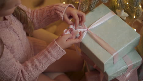 girl ties the bow of a christmas present