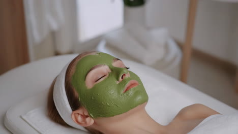 woman receiving a green face mask treatment at a spa