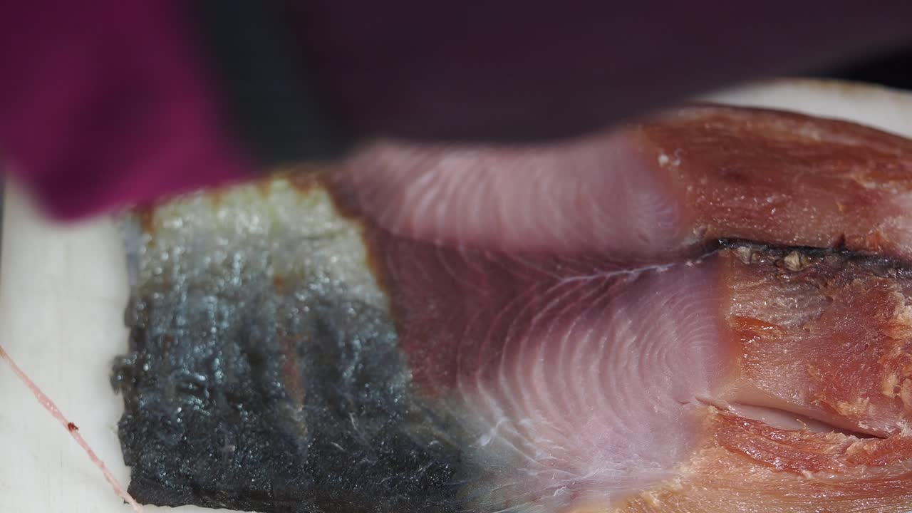 Kok skærer frisk fiskefilet på et skærebræt.
