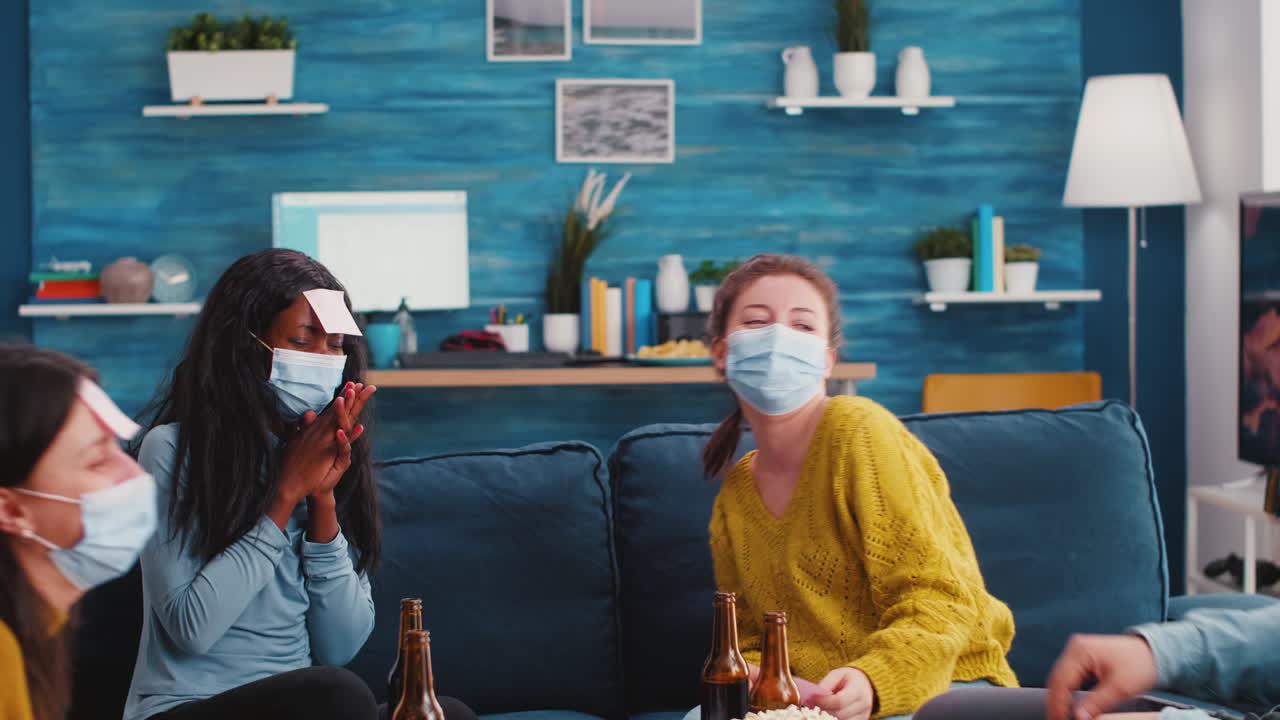 Group of friends with protective masks playing Who am I game