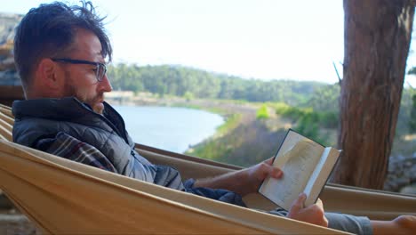 hombre leyendo un libro mientras se relaja en una hamaca 4k
