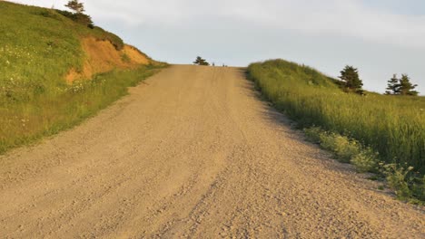 a quiet dirt road crosses a green hillside in the magdalen islands