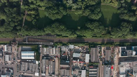 Rising-drone-shot-of-train-tracks-separating-nature-and-built-up-scrap-yard