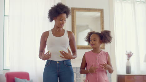 Happy-Black-mum-and-daughter-dancing-at-home-together