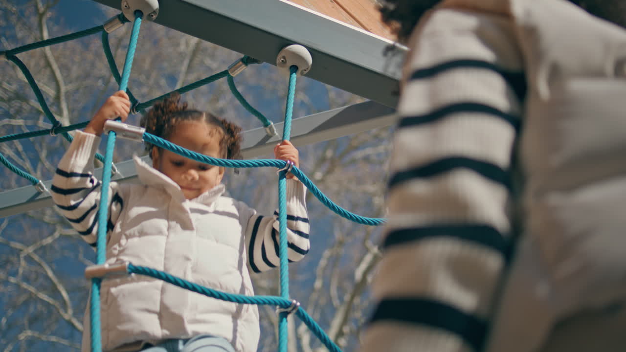 귀여운 아이가 엄마에게 다섯을 주고 로프 사다리를 가까이 올라갑니다. 소녀가 놀고 있습니다.