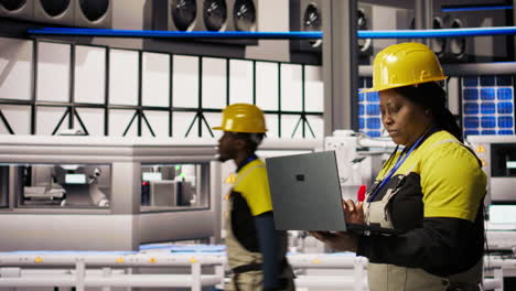 vertical video engineer walking in smart factory, using laptop to analyze iot sensors data