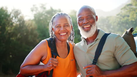 Portrait-Of-Senior-Couple-Going-For-Hike-In-Countryside-Standing-By-Car-Together