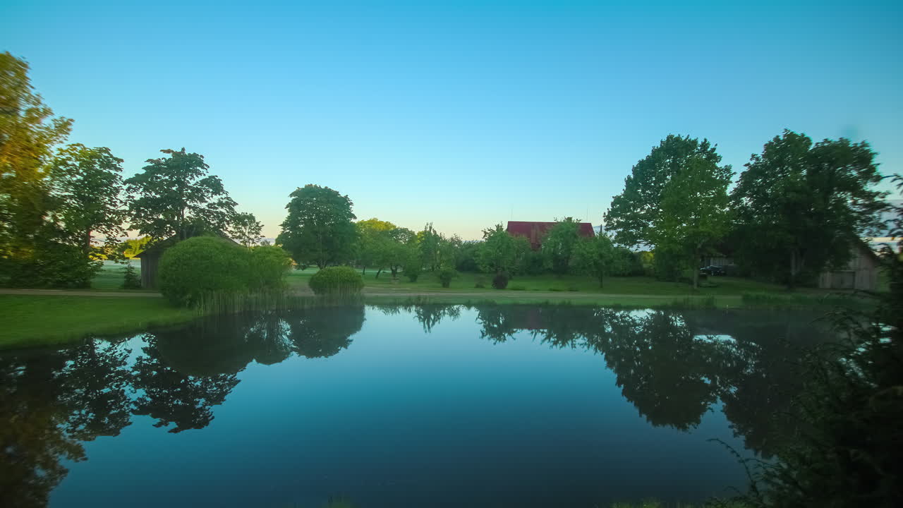 라트비아 의 아름다운 시골 호수 와  ⁇ 은 지붕 의 농장 위 에 움직이는 구름 들