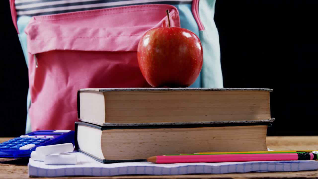 manzana en la pila de libros con el bolso escolar