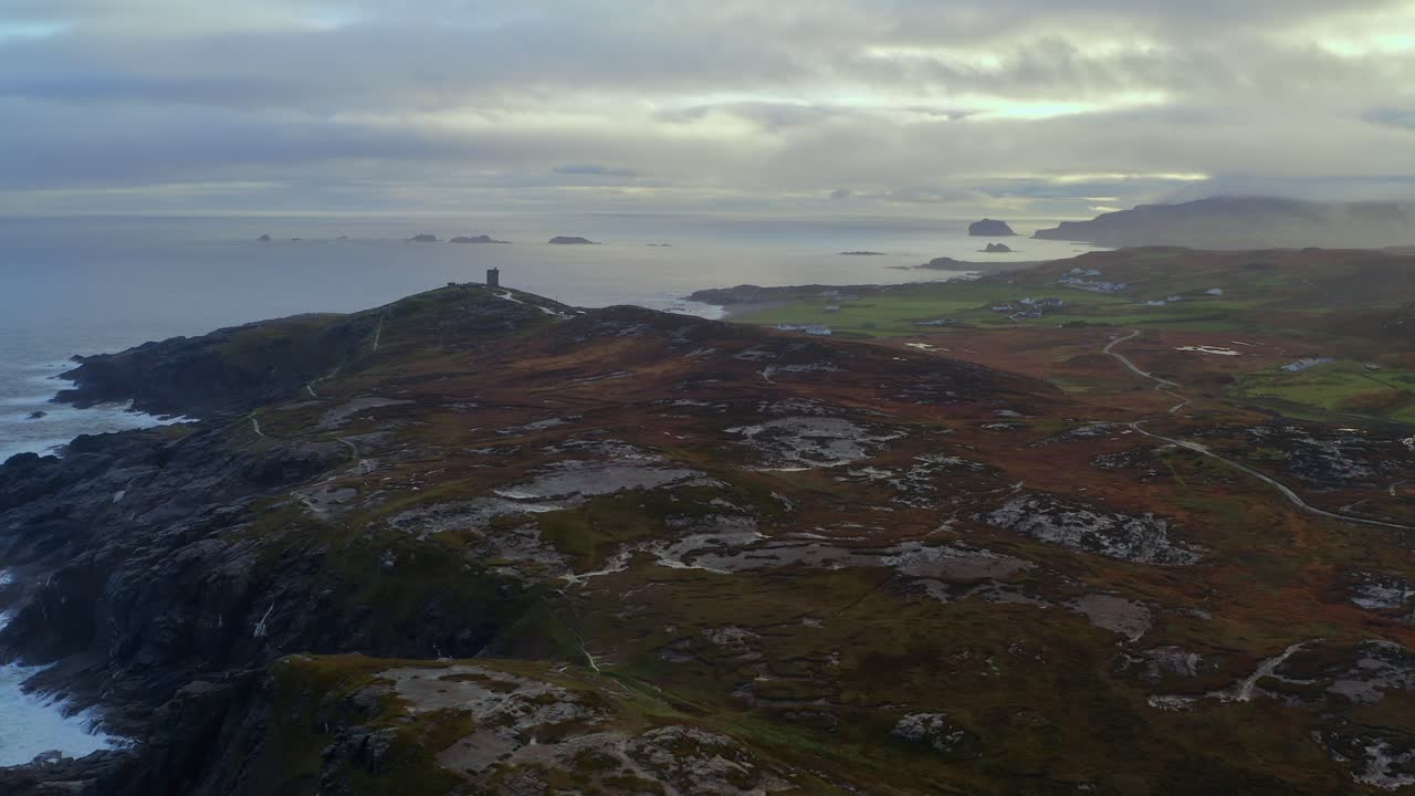 Aerial dolly shot showcasing the rugged terrain of Malin Head with the historic Malin Signal Tower in the background