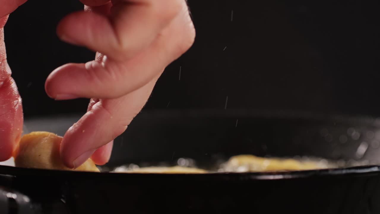 American chiken nuggets broiling on black frying pan close-up macro. Breaded nagget of chiken meat. Man cooking fast food. High quality 4k footage