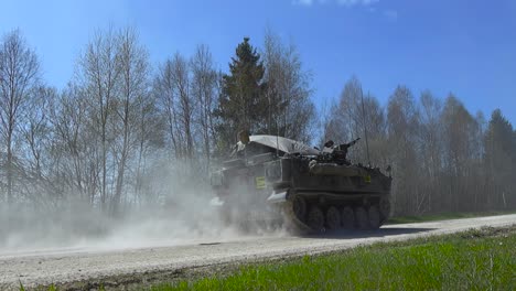 rare awesome military footage of a fv432 armoured vehilve with infanrty on it driving by on a dusty white countryside road in a ummer sunny forest during an battle exercise called siil 2025, slow-mo.