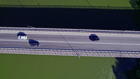 conduciendo muchos coches en el puente alrededor de la hierba verde y los árboles