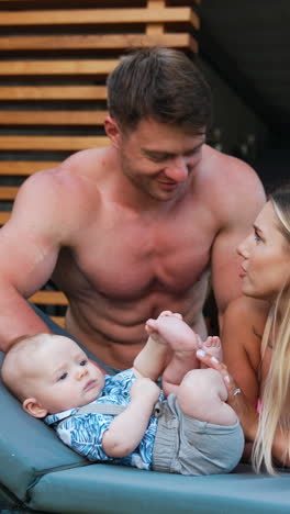 young parents resting with their infant baby. loving couple sit near the child lying on the deck chair.. vertical video