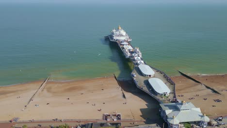 Flying-around-Eastbourne-Pier,-sea-front-and-beach