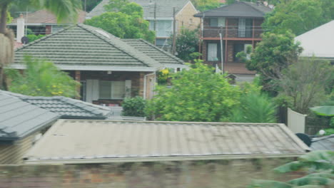 filmando desde la ventana de un tren durante el amanecer pasando edificios y patios traseros en sydney, australia