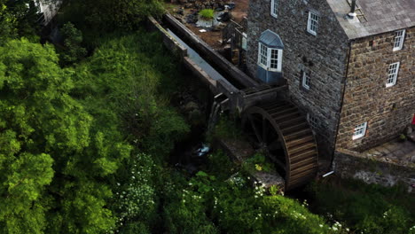 Incline-Hacia-Abajo-La-Toma-Aérea-De-Una-Casa-Antigua-Con-Un-Molino-De-Agua-En-Bushmills