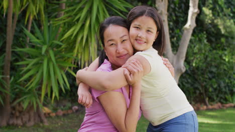 video of happy asian mother and daughter embracing in garden