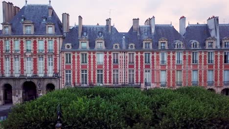 Vista-Panorámica-Desde-Un-Dron-Volando-Junto-Con-Casas-Históricas-De-Tres-Niveles-En-La-Place-Des-Vosges,-París,-Francia