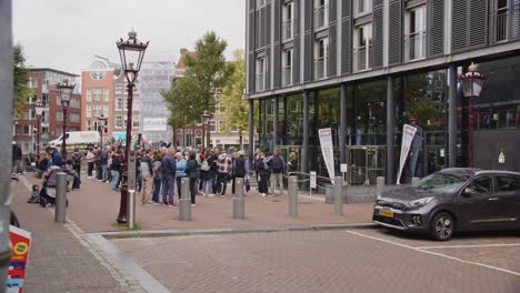 people waiting in line outside a modern building in amsterdam
