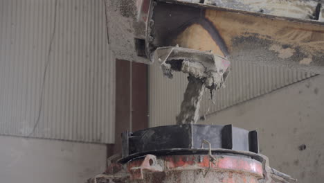 Concrete pouring process capturing a vertical stream of wet cement cascading from a chute, revealing industrial construction and material flow dynamics.