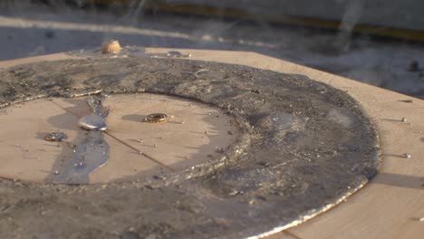 Slow-motion-close-up-of-lead-bubbling-in-round-wooden-mold