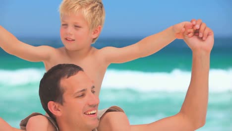 Father-man-with-his-son-on-his-shoulders-on-the-beach