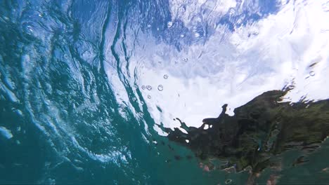 perspectiva submarina única desde debajo de una ola que rompe la costa rompiendo en la orilla