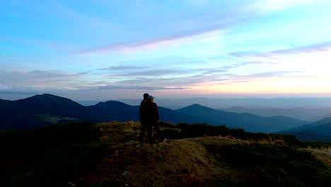 the man and a woman standing on the top of the mountain on the sunset background