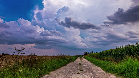 Time-Lapse-of-Fluffy-white-Clouds-swirling-around-above-an-unsealed-Country-Road